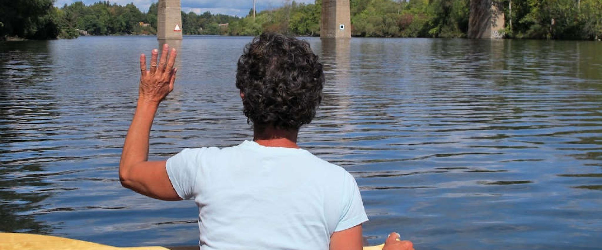 A paddler waves as she watches a train crossing a bridge across the Rideau Waterway, in Ottawa, ON 
