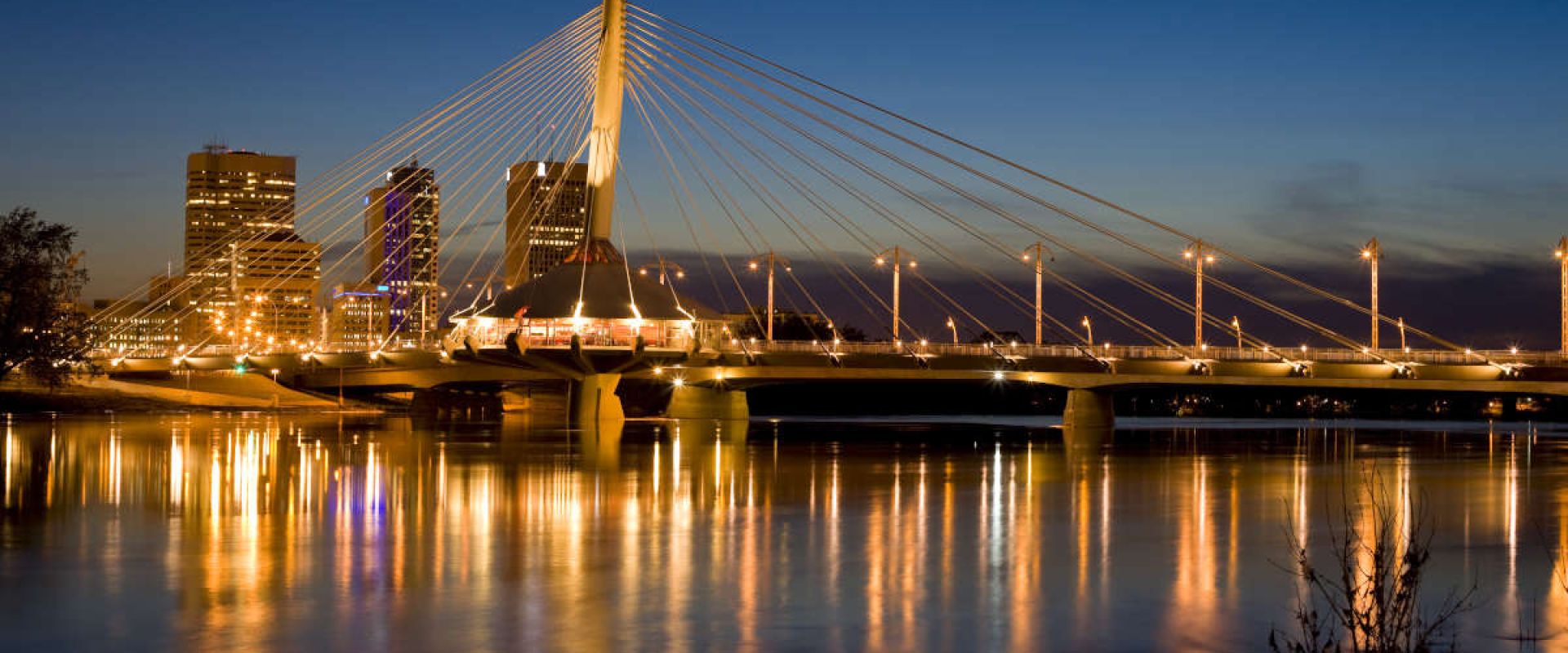 City lights reflect upon the Red River at dusk.