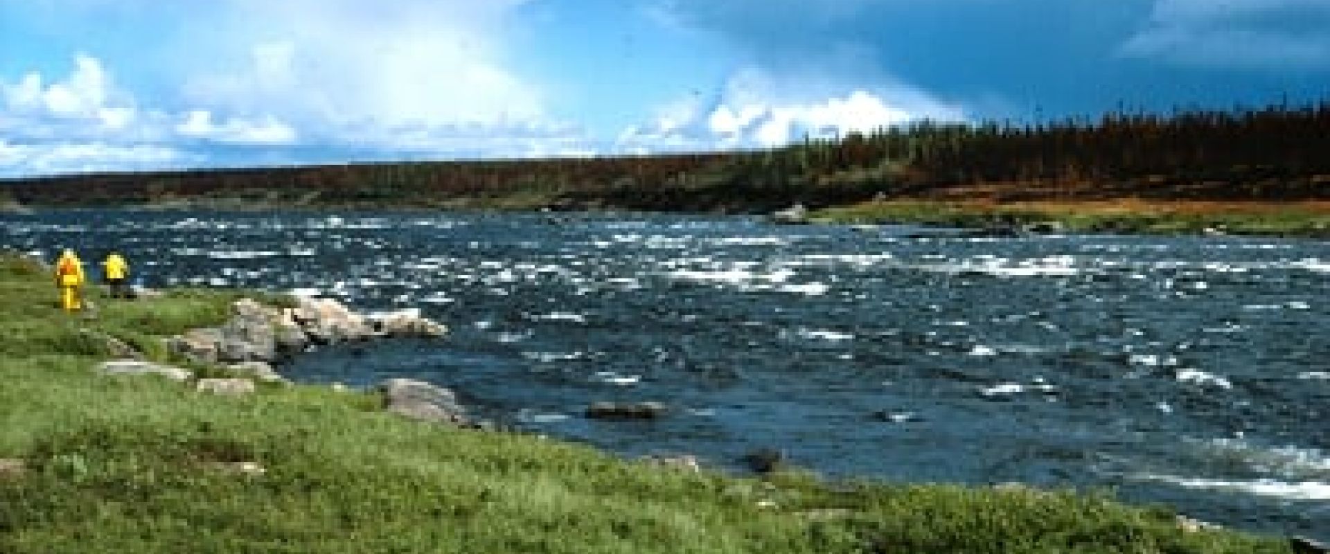 Two men in yellow walk the shoreline alongside Deaf Rapids. (Photo: Manitoba Government)